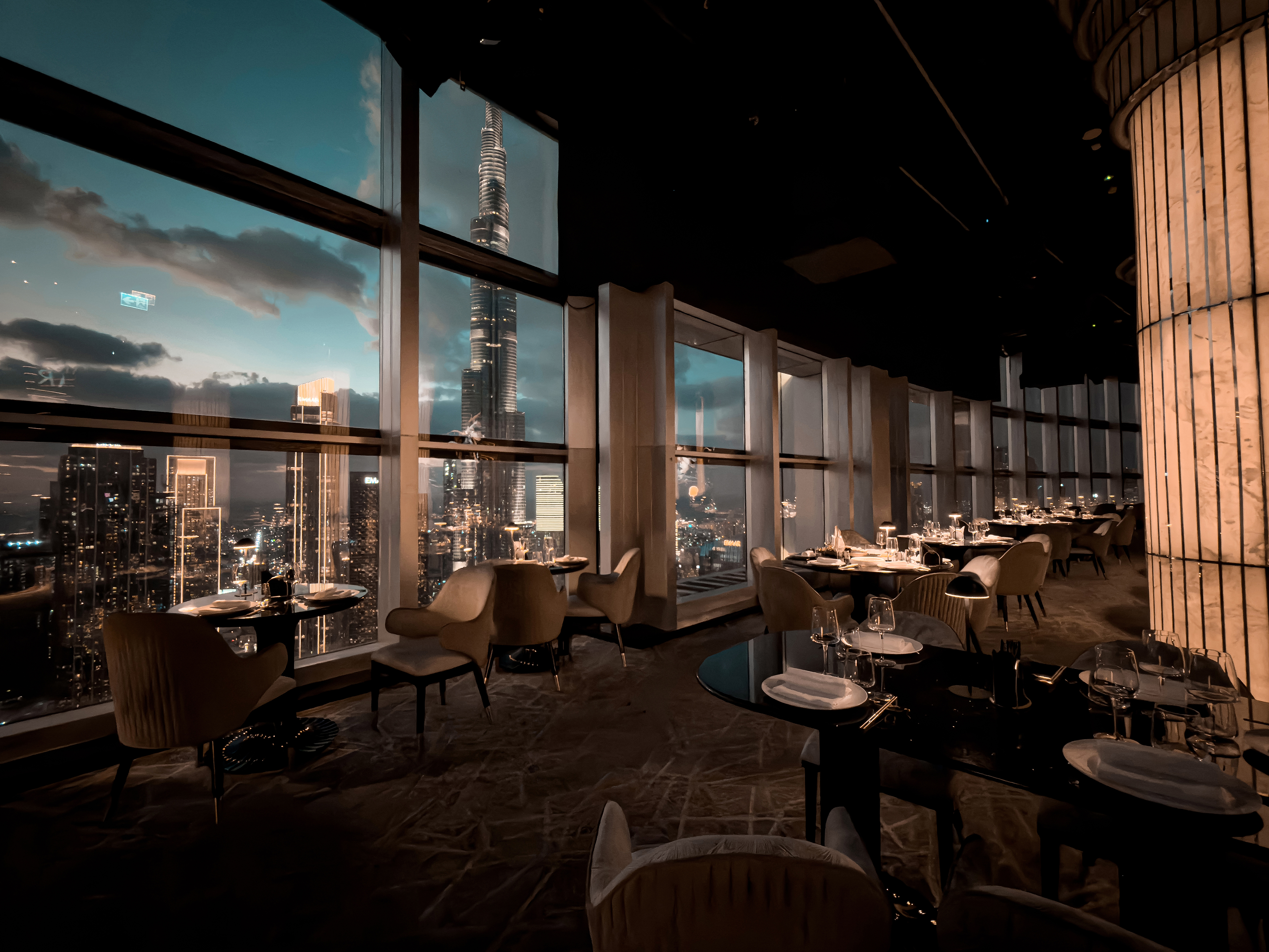 BIRDS Dubai dining room with Burj Khalifa visible through the windows at dusk.