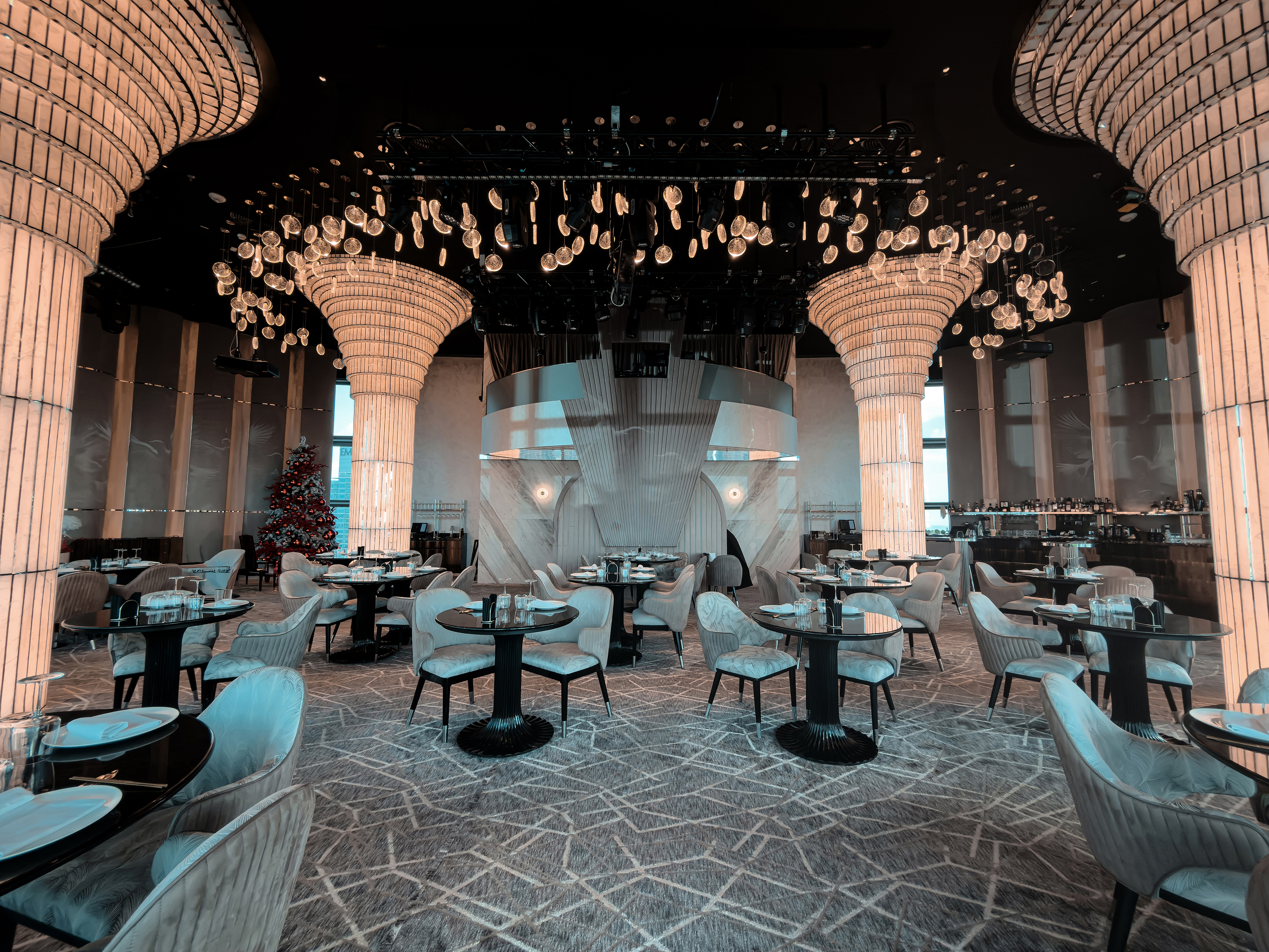 BIRDS Dubai theatrical dining room with illuminated columns and set tables.