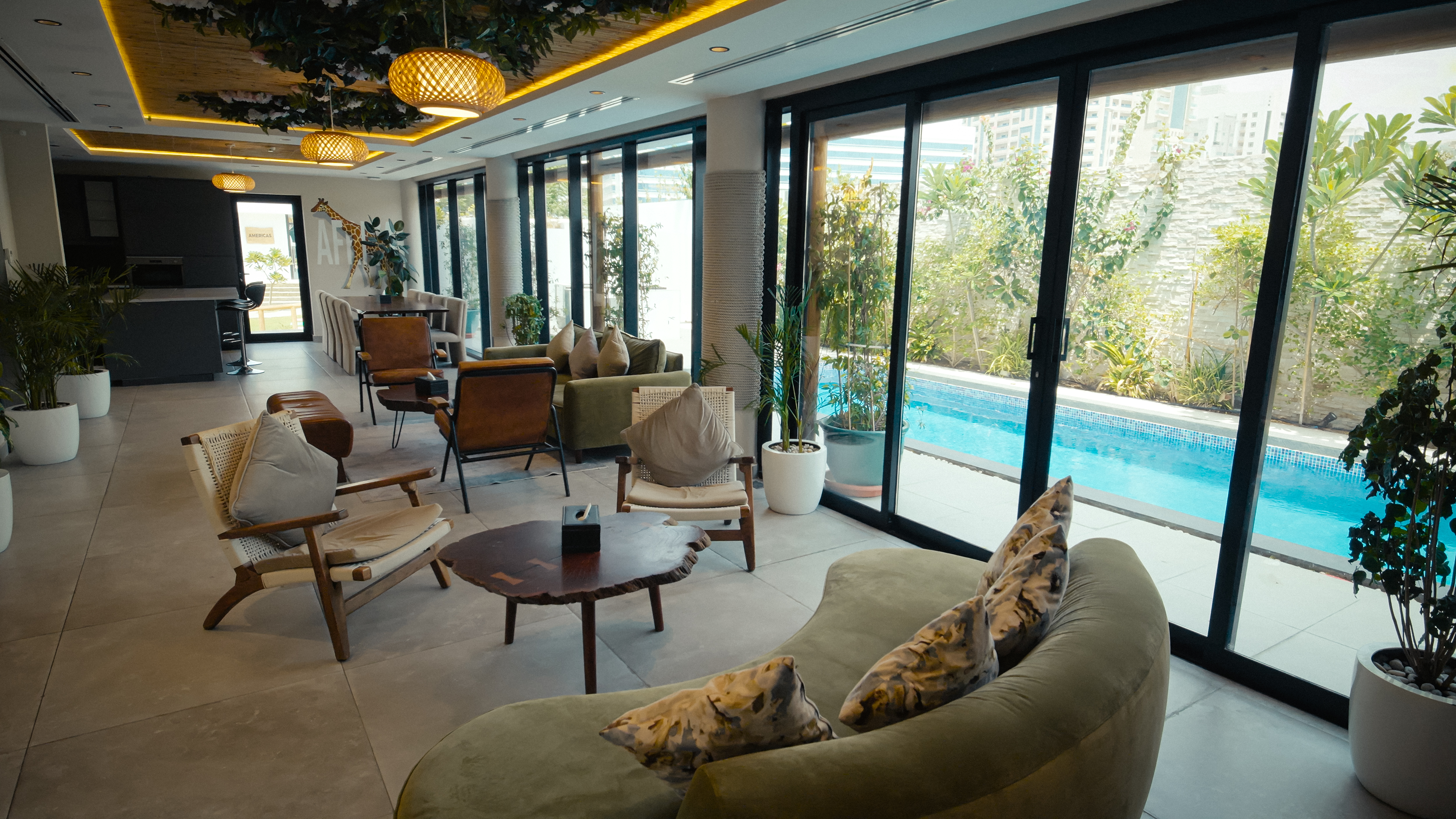 NAS House lounge and poolside seating with daylight through glass doors.