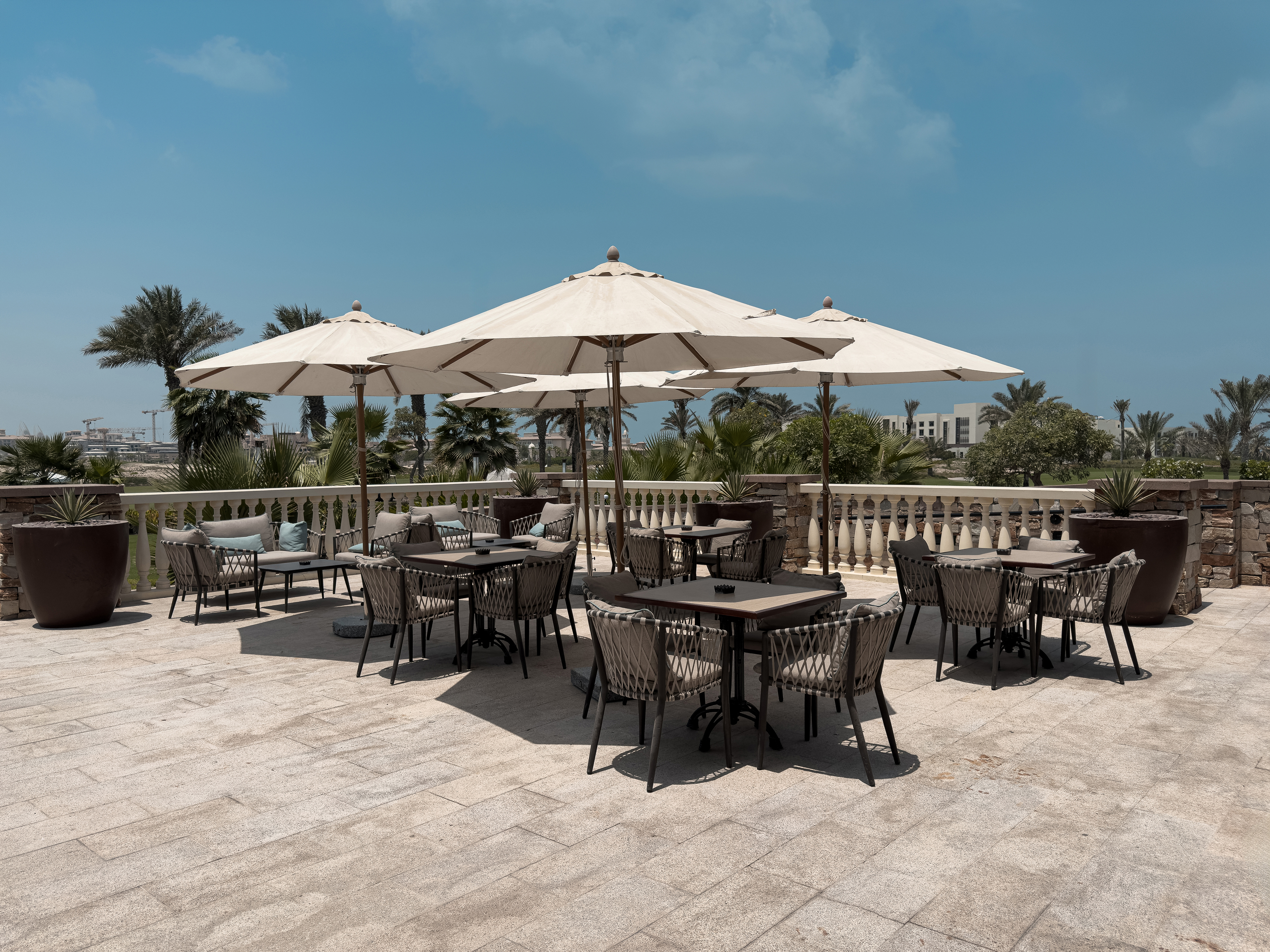 Terrace seating at Saadiyat Beach Golf Club with umbrellas and course views.