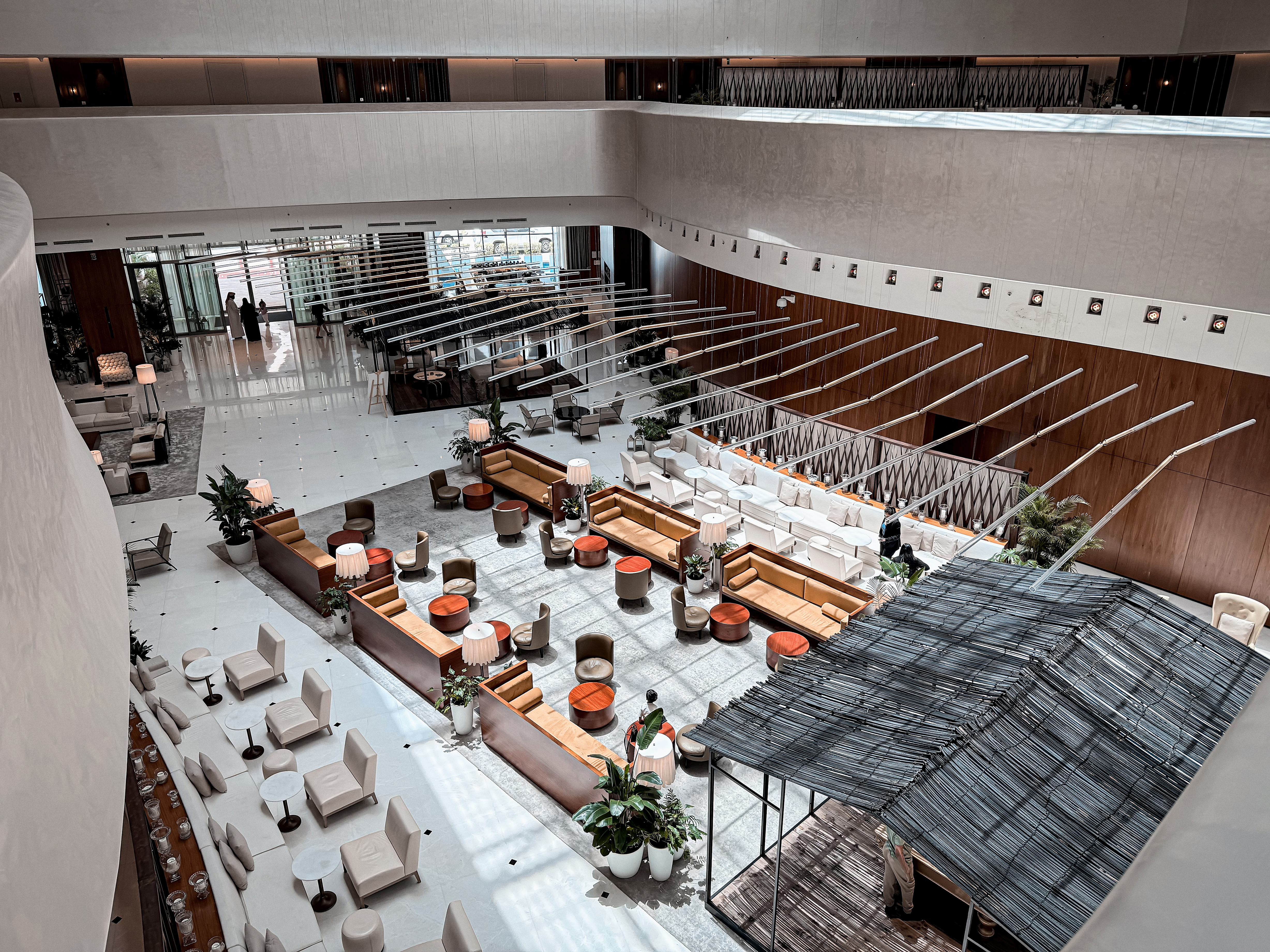 Bright hotel ballroom foyer with plants and seating.